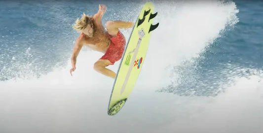 Surfer on a neon yellow surfboard carves a turn on a breaking wave.